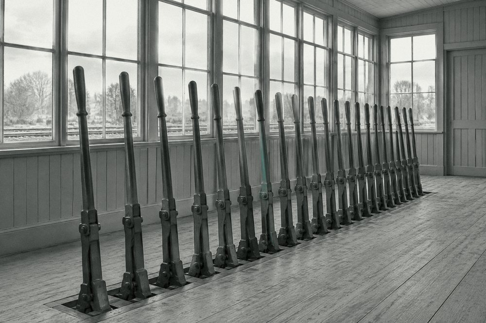 A row of signal levers in an empty signal box; one lever is painted teal.